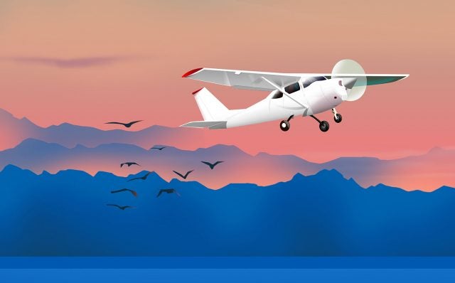 Small plane flying over the water.