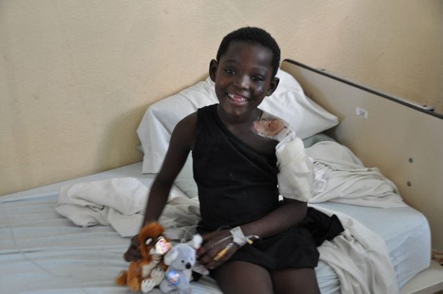 A young boy, 6 or 7, in Haiti heavily bandaged, smiling at the camera with a gap-toothed grin following the 2010 earthquake.