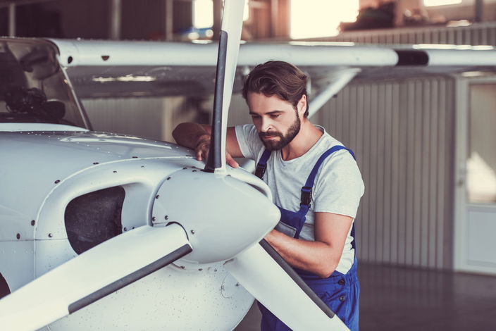 Aircraft mechanic standing next to airplane engine